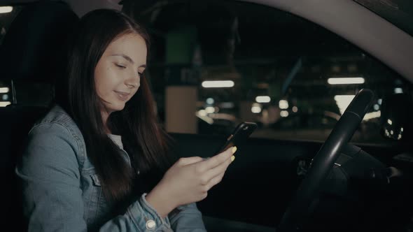 Woman Uses an Application on His Phone While Sitting in the Car in the Parking Lot alt