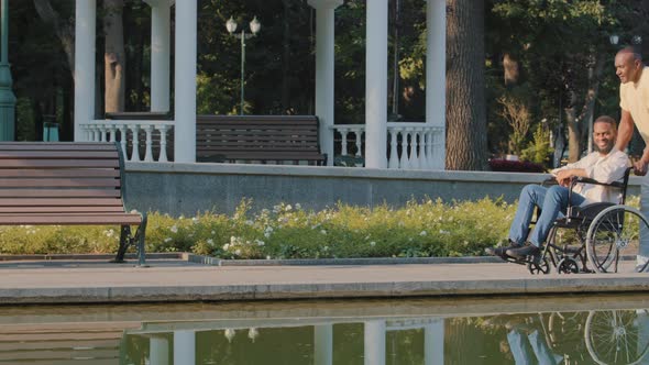 Young Disabled Man Enjoys Walk in City Park By Water on Sunny Summer Day alt