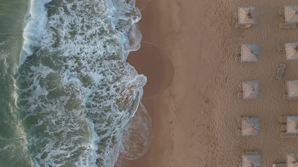 Sandy beach with straw sunshades and sunbeds alt
