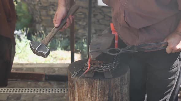 Blacksmith of the medieval era forges red-hot iron with a sledgehammer.
