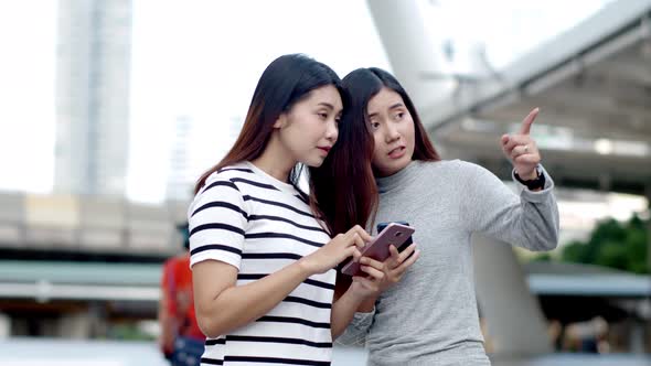 Two Teenager travellers checking location map on smartphone 