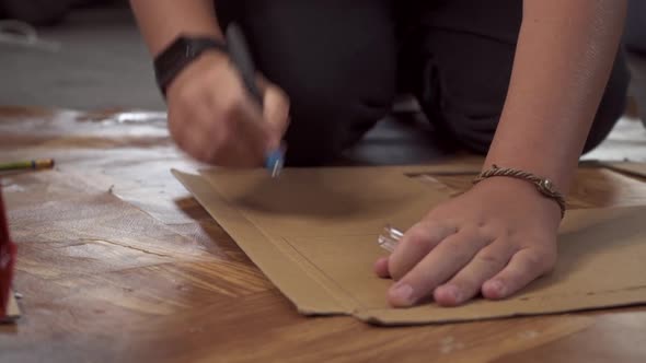 a Schoolboy Boy Cuts a Cardboard Craft with a Cutter