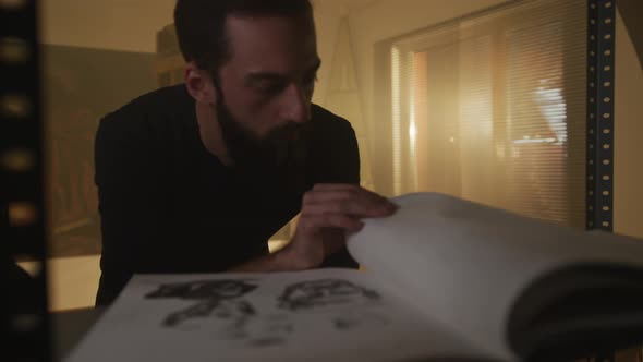 Artist Analyzing a Sketch in A Sketchbook alt