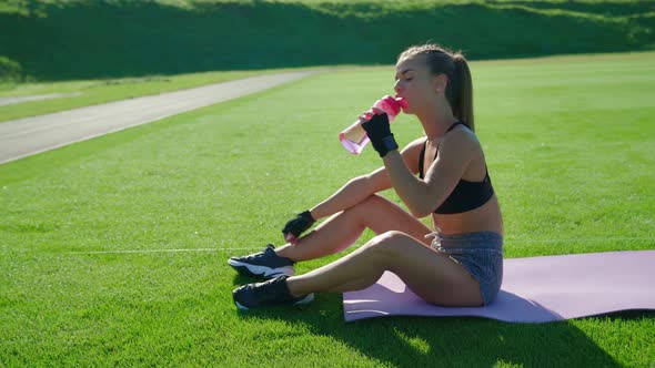 Woman Drinking Water After Training at Stadium alt