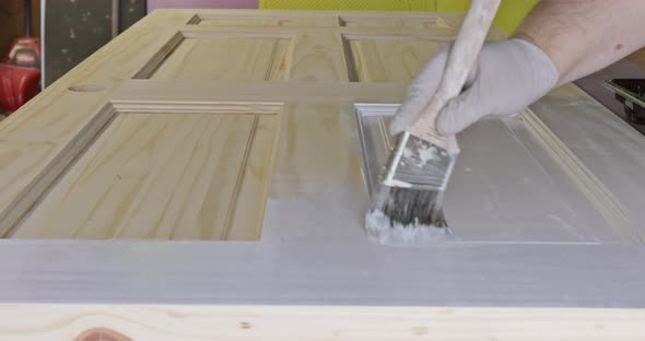 Handyman home renovation painter of painting doors trim using hand paint brush painting with gloves alt