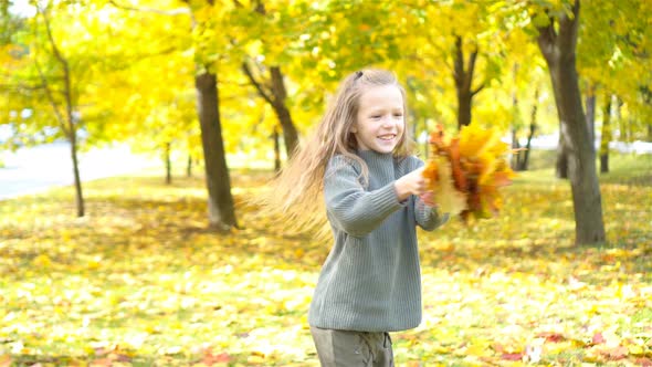Portrait of Adorable Little Girl with Yellow Leaves Bouquet in Fall