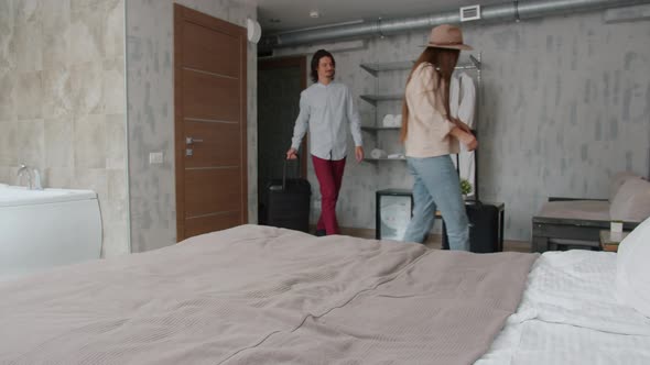 Husband and Wife Tourists Entering Hotel Room Falling on Bed Smiling Enjoying Rest alt