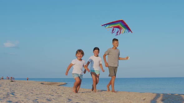 A Happy Children Play Kite Together on the Beach. Summer Holidays. alt