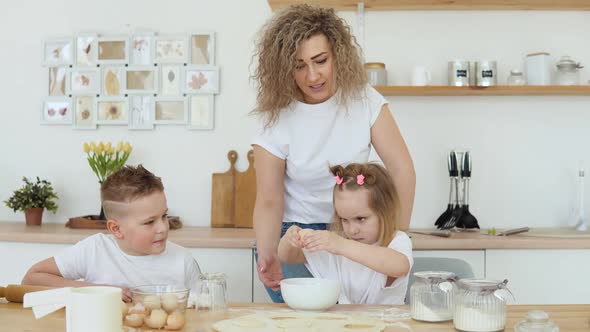 The Girl Breaks an Egg Into a Bowl on Her Own While She Cooks with Her Mother and Brother in the alt