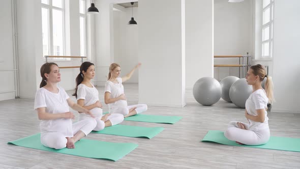 Calm Concentrated Pregnant Women Sit on Fitness Mat Raising Hands Up