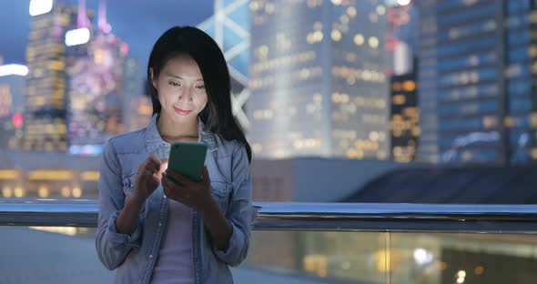 Young woman looking at mobile phone at night alt