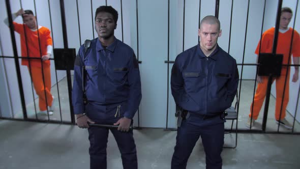 Guards Stand in the Background of Prison Cells alt