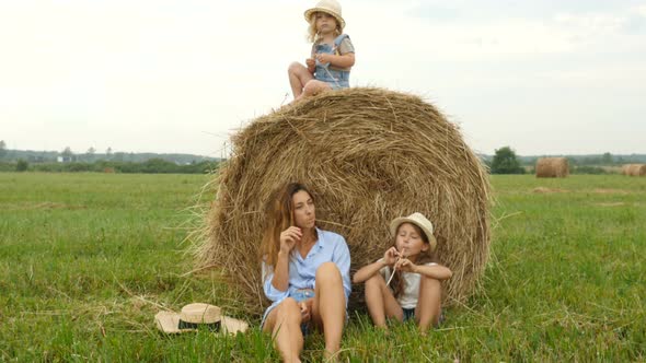 Mom With Children Relaxing on Grass Field. Farmer Family Walking on the Field alt