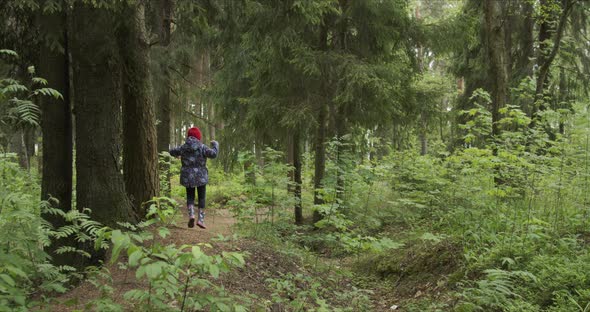 Back View of Little Girl on Red Hat Walking on Forest Path alt