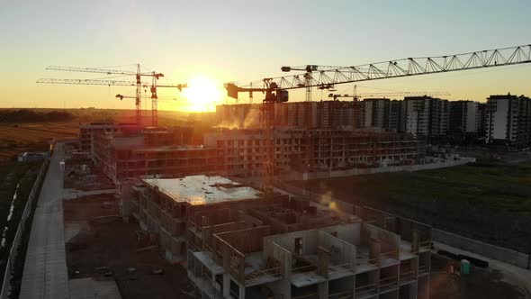 Silhouettes of Construction Cranes at Sunset. Drone Video alt