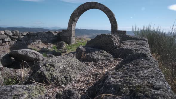 Arched architectural detail in Monsanto village and panorama in background, Portugal. Pedestal up alt
