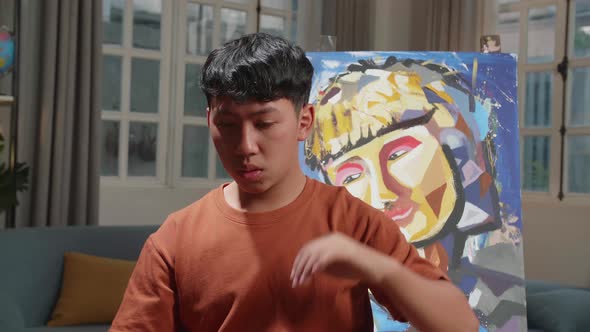 Asian Artist Boy Holding Paintbrush Wipe The Sweat Before Crossing His Arms And Smiling To Camera alt