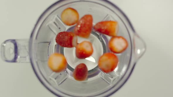 Strawberries fall into mixer from a hands