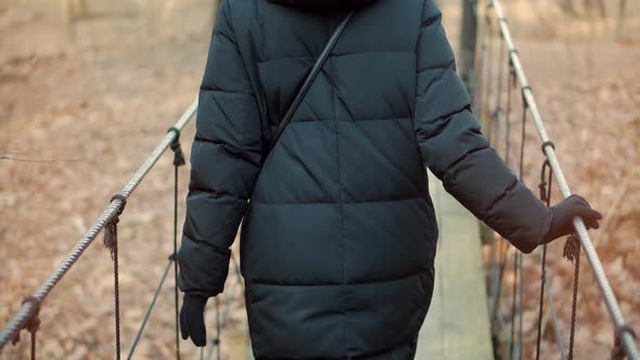 Woman Walking On Suspension Bridge. Tourist Walkway In Forest. Traveler Explore Forest. alt