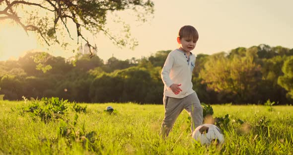 Happy Boy Running with Soccer Ball Running at Sunset in Summer Field alt