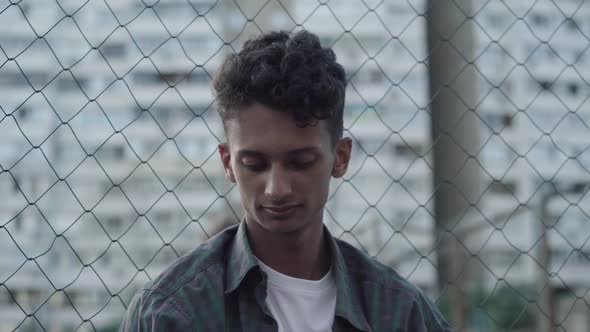 Close-up Portrait of Sad African American Teenager Looking Back at Guys Playing Football and Turning alt