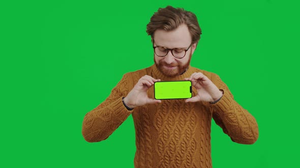 Middleaged Caucasian Entrepreneur Holding Smartphone with Green Screen and Smiling Medium Studio alt
