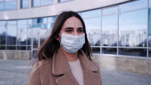A Beautiful Woman Is Walking in a Protective Mask on the Street. The Concept of Health and Safety