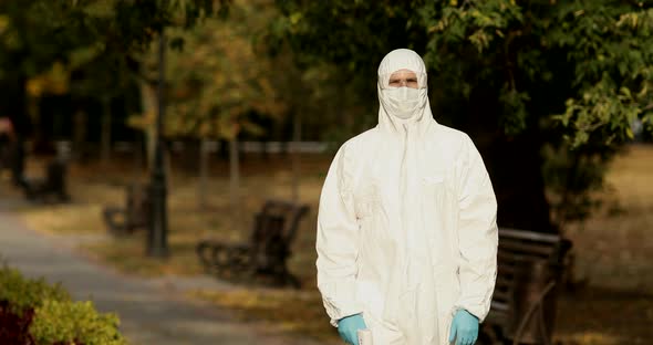 Doctor in protective antiviral costume and face medical mask standing on street.