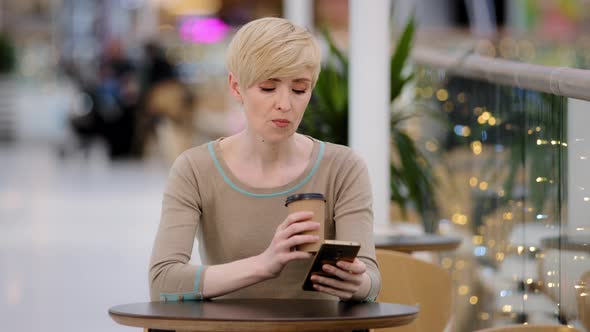 Middle Aged Adult Woman Caucasian Lady with Short Haircut Sitting at Cafe Table Drinking Coffee Tea alt