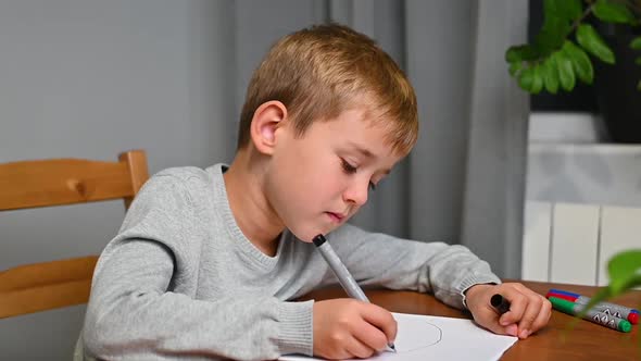 Boy draws while sitting at the table