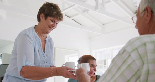 senior male and female friends sitting at a table together socialising before their ballroom dancing alt