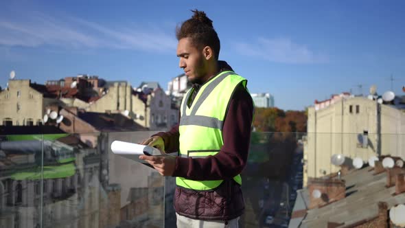 Young Intelligent African American Man Analyzing Project Standing on Urban Rooftop in Sunshine alt