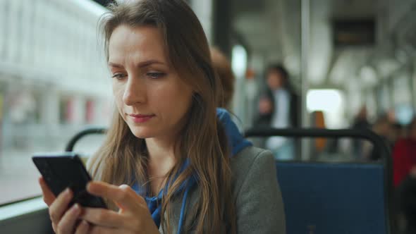 Woman in Tram Using Smartphone Chatting and Texting with Friends alt