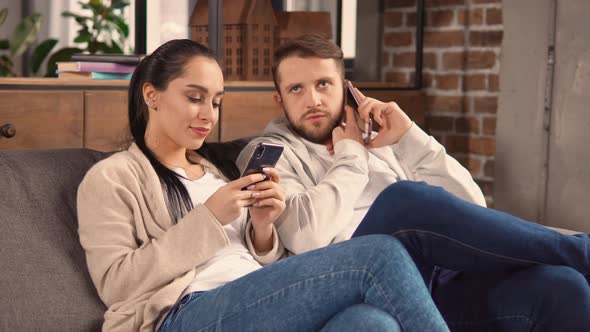 Lazy Couple Sitting on Couch and Using Their Phones alt
