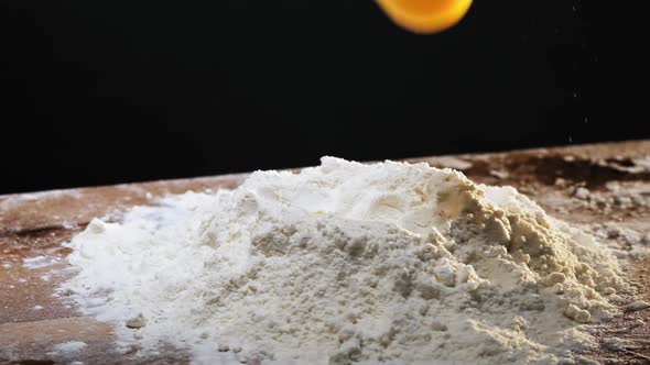 Raw Egg and Broken Shell Fall Down Into Flour Pile on Table alt