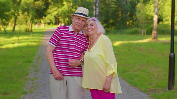 Senior Old Stylish Tourists Couple Grandmother Grandfather Walking in Summer Park and Making a Kiss alt