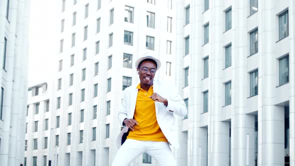 Joyful man in suit hat and glasses jumps and dances smiling alt