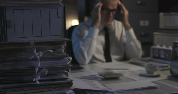 Stressed businessman working overtime in the office, he is having a bad headache