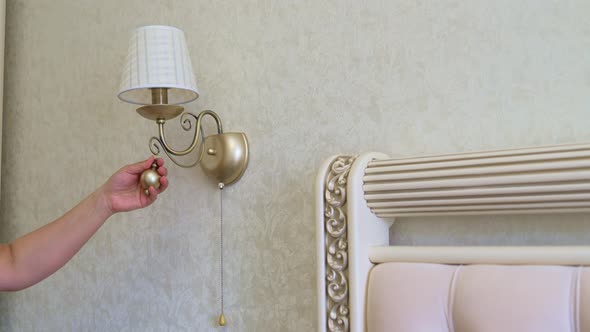 Male Electrician Hangs Decoration and Turns on the Light on Sconces on the Wall alt