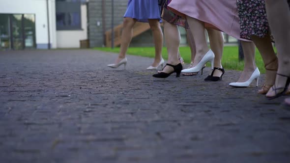 a Group of Women in Evening Dresses and Highheeled Shoes Move Synchronously on the Pavement