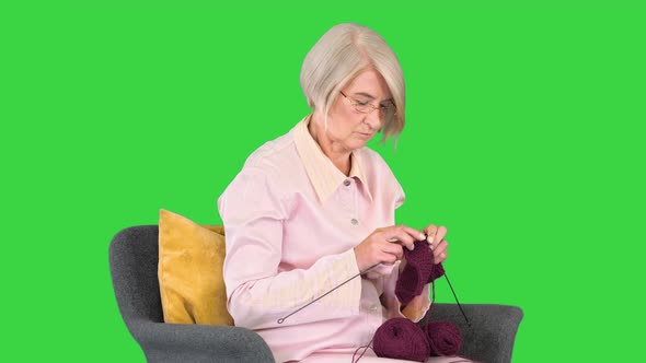Elderly Woman Knitting Sitting on a Chair on a Green Screen Chroma Key alt