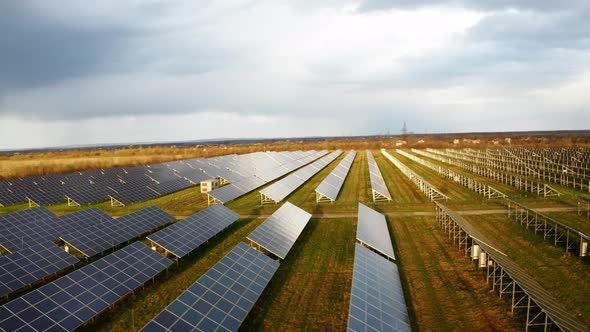 Solar energy in Denmark. Flying above Solar Power Station Panels in the fields. Storm rain clouds alt