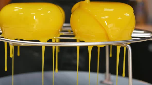 Closeup Dolly Shot DOF Pour Yellow Mirror Icing Onto Round Mousse Cakes on a Wire Rack