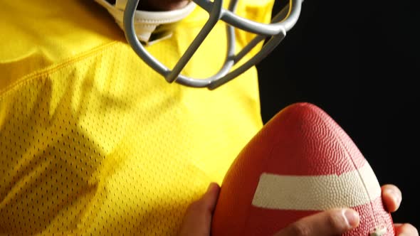 American football player holding ball against black background 4k alt