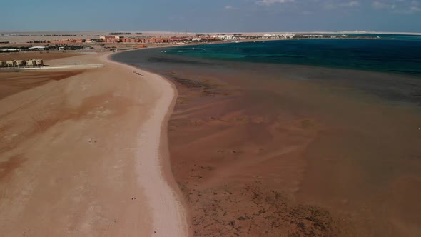 Quadcopter flight over the Red Sea. Low tide. Sand. Desert. Hotel in the distance. Egypt. alt