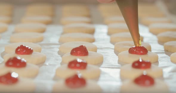Baker preparing butter cookies with strawberry jam and powdered sugar alt
