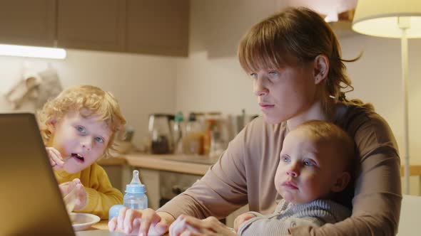 Mother of Two Kids Working on Laptop at Home alt