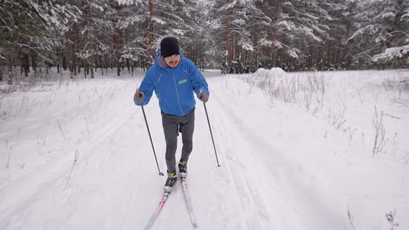 A Young Man Is Engaged in Crosscountry Skiing in the Winter Forest alt