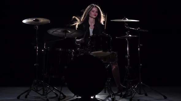 Drummer Girl Starts Playing Energetic Music, She Smiles. Black Background. Slow Motion alt