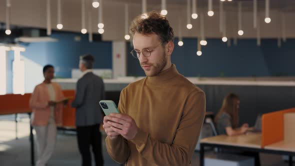 Portrait of Caucasian Businessman in Glasses Looking at the Camera After Using His Smartphone alt